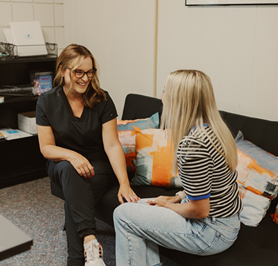 Laura smiling at a patient while resting her hand on the patients knee