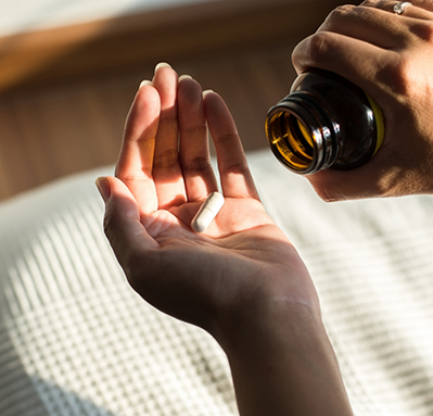 Person turning over a pill bottle to drop a pill in their hand