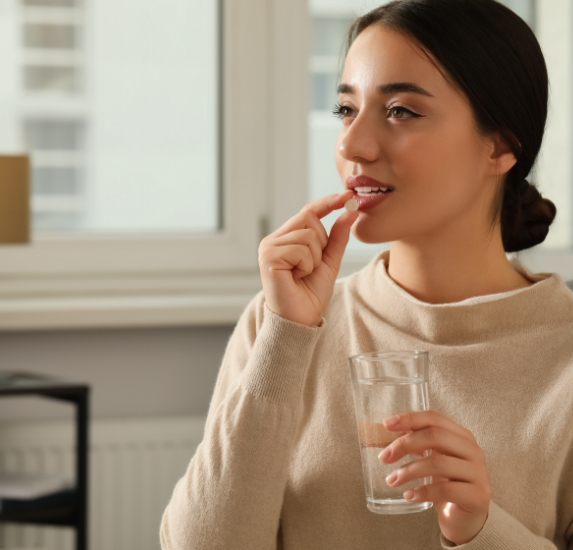 Woman taking a pill with a glass of water